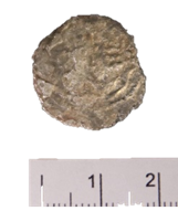 A piece of silver coin next to a ruler  Description automatically generated